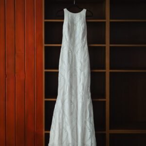 a wedding dress hanging in front of a bookcase